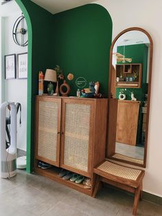 a wooden cabinet sitting next to a green wall