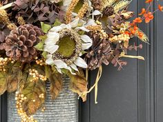 a vase filled with lots of different types of flowers next to a black wooden door