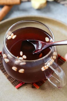 a glass cup filled with liquid sitting on top of a table next to cinnamon sticks