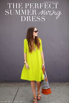 a woman in a yellow dress is standing on the sidewalk with her handbag and purse