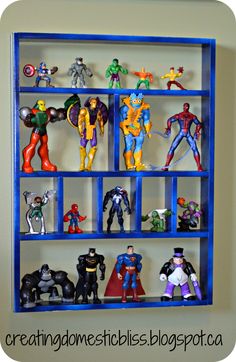 a blue shelf filled with action figures on top of a white wall next to a window