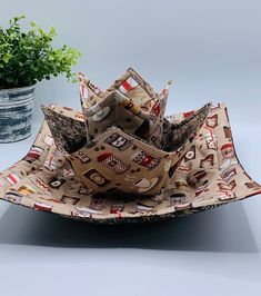 an origami sculpture made out of paper on top of a table next to a potted plant