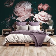 a bed with pillows and blankets in front of a floral wall mural on the wall