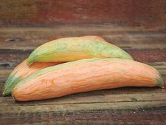 two gourds sitting on top of a wooden table next to each other, one orange and the other green