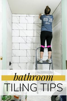 a woman on a ladder painting the walls in a bathroom with text overlay that reads bathroom tiling tips