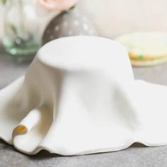 a white hat sitting on top of a table next to a vase filled with flowers