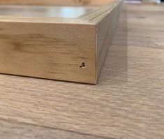 a close up view of a wood frame on a wooden table with a black cat in the background