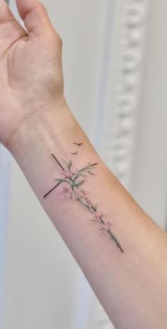 a woman's arm with a cross and flowers tattoo on the left side of her arm