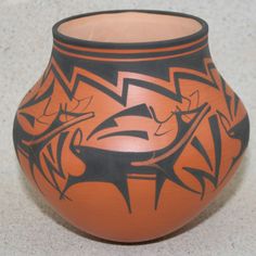 an orange and black vase with designs on it