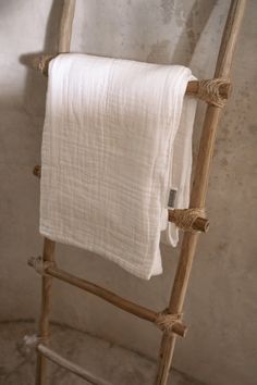 a white towel is hanging on a wooden ladder