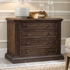 a wooden dresser sitting in a living room next to a chair and vase on top of it