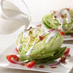 lettuce with dressing being drizzled over it on two white plates