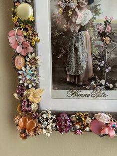 there is a picture frame decorated with flowers and beads on the wall next to it