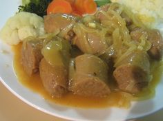 a white plate topped with meat covered in gravy and vegtables