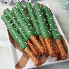 green and white dessert sticks with sprinkles on them in a square plate