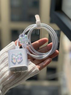 a person holding an apple charger in their hand with a heart shaped plug attached to it