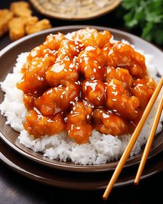 a plate with rice, chicken and chopsticks on it