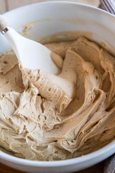 a white bowl filled with peanut butter on top of a wooden table