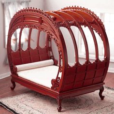 a red bed frame sitting on top of a wooden floor next to a white rug