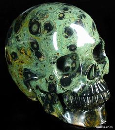 a green and black skull with holes on it's face