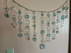 there is a wall hanging made out of glass beads and silver chains on the wall