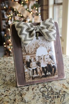 an old photo with a bow on it is sitting in front of a christmas tree