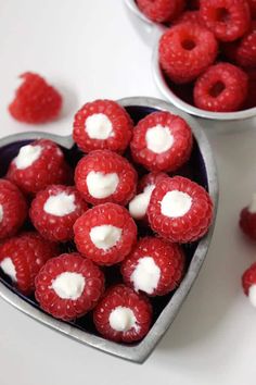 some raspberries in a heart shaped bowl with marshmallows on top