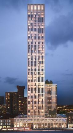 a very tall building sitting in the middle of a large city at night with lights on it