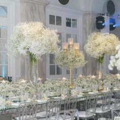 the tables are set up with white flowers in vases and candles on each table