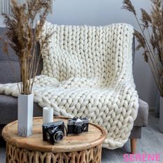 a white knitted blanket sitting on top of a couch next to a coffee table