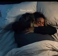 a woman is sleeping in bed with her head on the pillow and arms wrapped around her