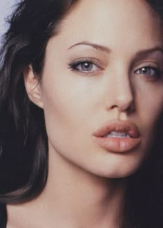 a close up of a woman with long hair and blue eyes wearing a black top