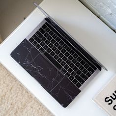 an open laptop computer sitting on top of a white desk next to a sign that says support