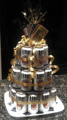 a cake made out of beer cans with gold ribbons and bows on the top tier