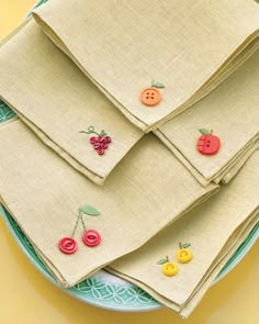 four napkins with buttons on them sitting on a blue checkered tablecloth background