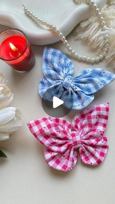 three bows and a candle sitting on a table next to some pearls, beads and flowers