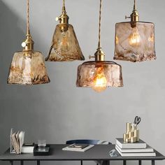 three lights hanging from the ceiling above a table with books and other items on it