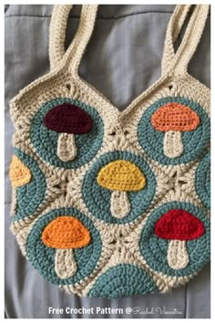 a crocheted bag with mushrooms on it sitting on top of a bed next to a pillow