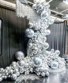 a very tall christmas tree made out of silver baubles and balls on a black table