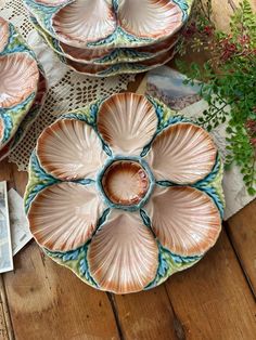 three plates with flower designs on them are sitting on a table next to a potted plant