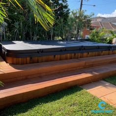 a hot tub sitting on top of a wooden deck next to a lush green yard