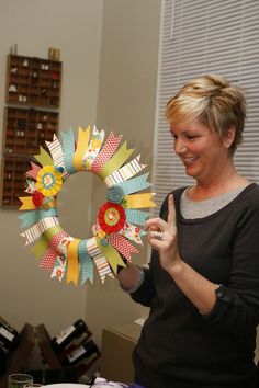 a woman is holding up a paper wreath