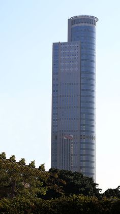 a very tall building sitting in the middle of a tree filled area next to trees