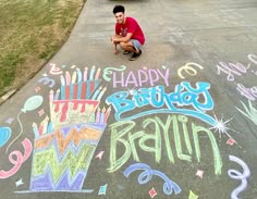 a man kneeling down in front of a chalk drawing on the sidewalk that says happy birthday