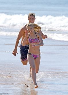 a man and woman running on the beach