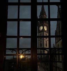 a clock tower seen through a window at night