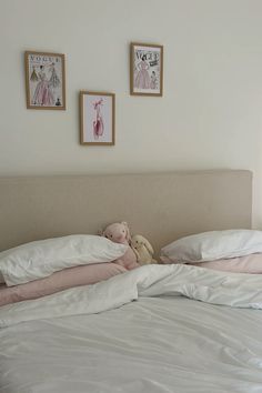 there is a teddy bear on the bed with two framed pictures above it and another stuffed animal