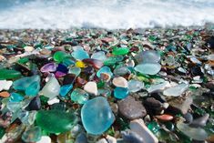 many different colored glass pieces on the beach