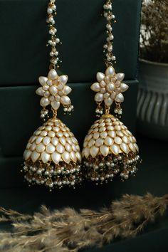 This statement pair features patchi work in a delicate creamish white color and embellished with pearls and green stones. These earrings with their artistic aesthetics are undoubtedly a stunner. Closure - Push Back Style Tip - Wear this with almost anything Indian for a rich and royal look because nothing more regal than patchi work earrings. We love teaming this with classy chiffon sarees or zari silk sarees. Also looks best when worn with your royal whites, off whites and gold. We recommend st Luxury Traditional Pearl Earrings With Latkans, Luxury Green Jhumkas As Gift, Luxury Green Jhumkas For Gift, Luxury Hand-set Green Jhumkas, Luxury Green Hand Set Jhumkas, Luxury Green Jhumkas For Diwali, Luxury Green Elegant Jhumkas, Luxury Green Chandbali Jhumkas, Luxury Green Jhumkas With Hand Set