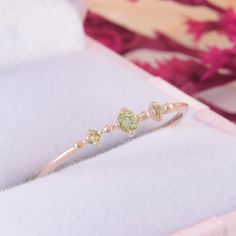 a yellow diamond ring sitting on top of a white box with pink flowers in the background